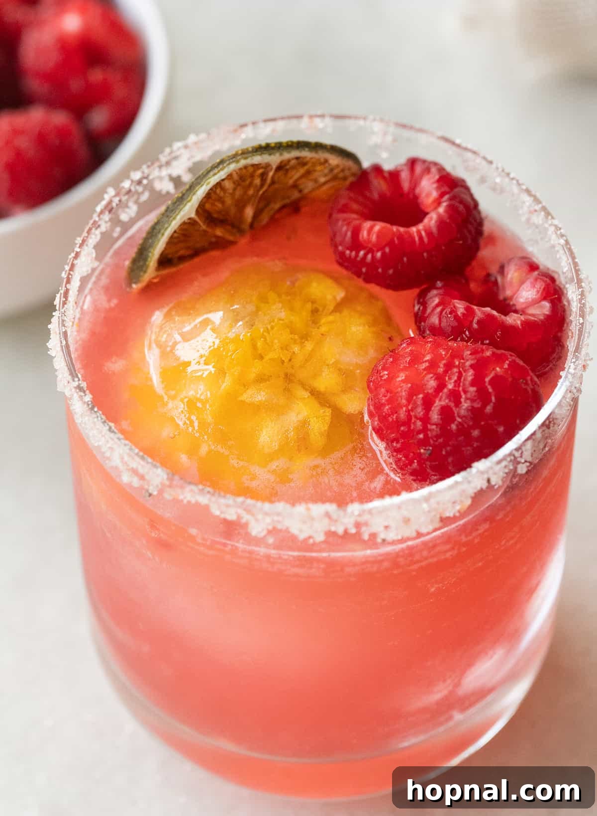 A beautifully crafted Margarita made with natural fruit, possibly raspberry, for a refreshing taste.