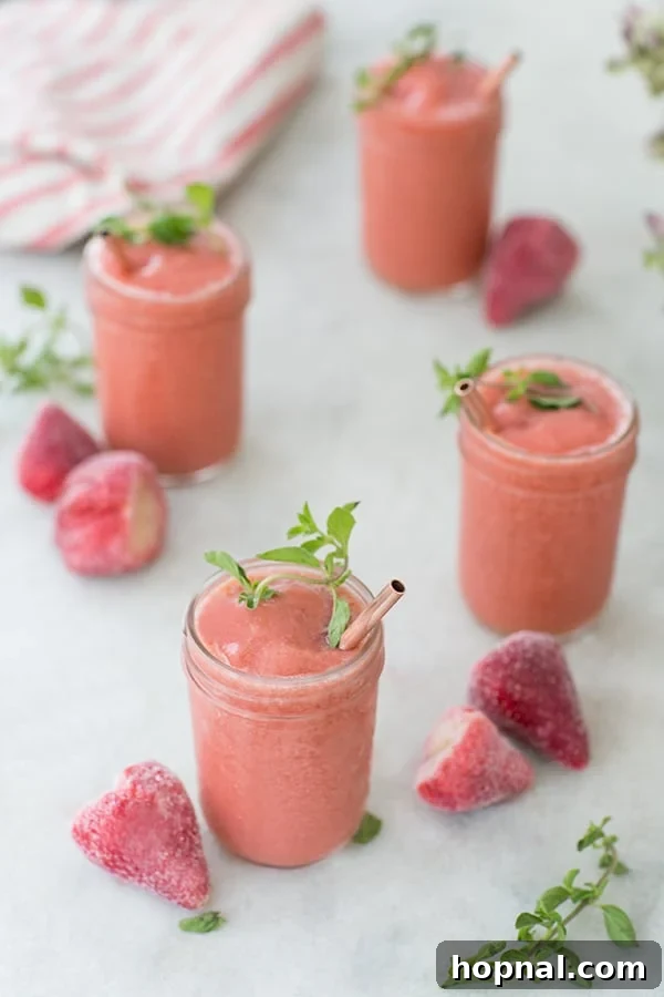 Two refreshing Strawberry Frosé cocktails with copper straws and fresh mint garnishes.