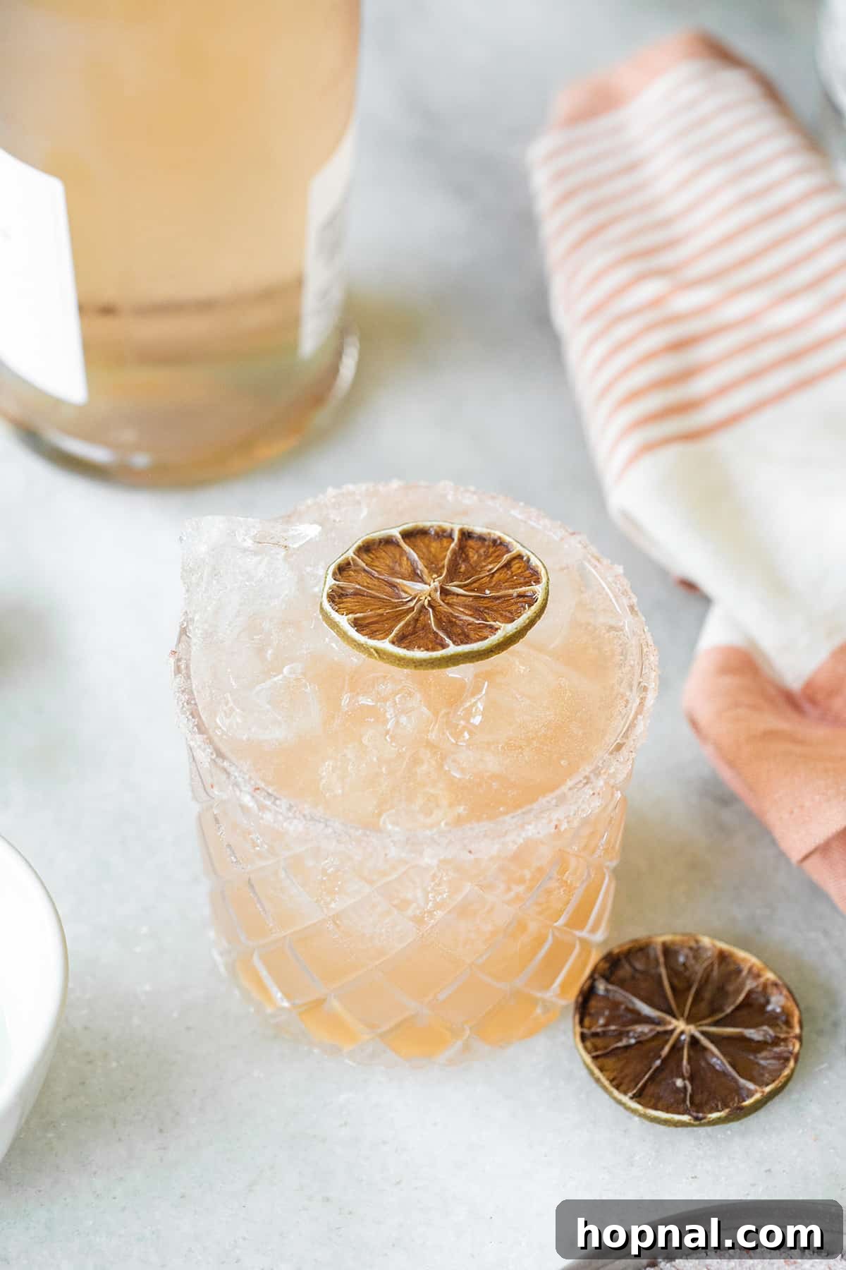 Pink sparkling margarita in a glass with a salted rim and lime garnish.
