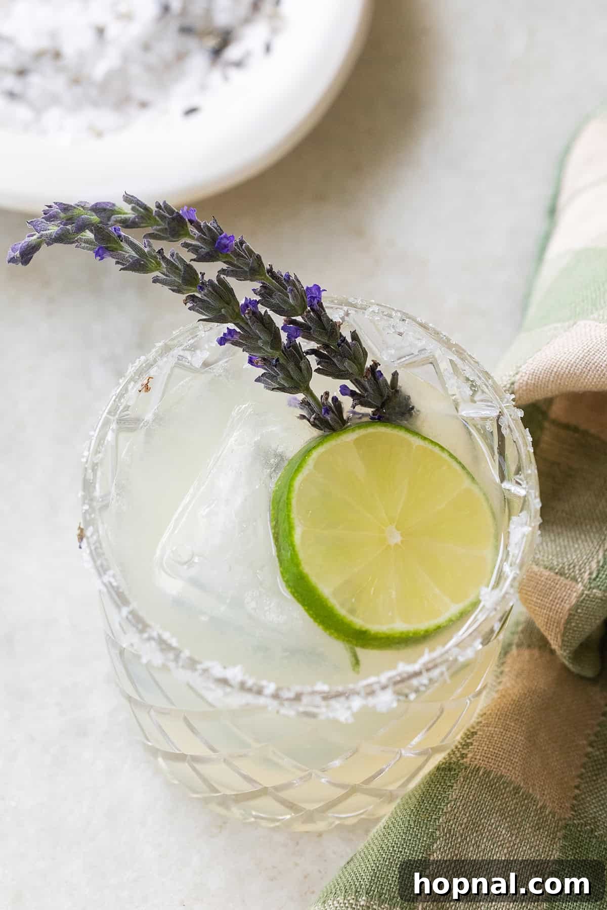 Lavender margarita with a delicate lavender sprig and a lime slice, offering a floral twist.