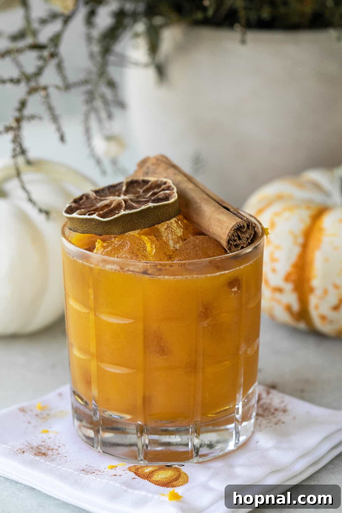 Pumpkin spice margarita in a glass with a cinnamon stick and lime wheel garnish, perfect for fall.