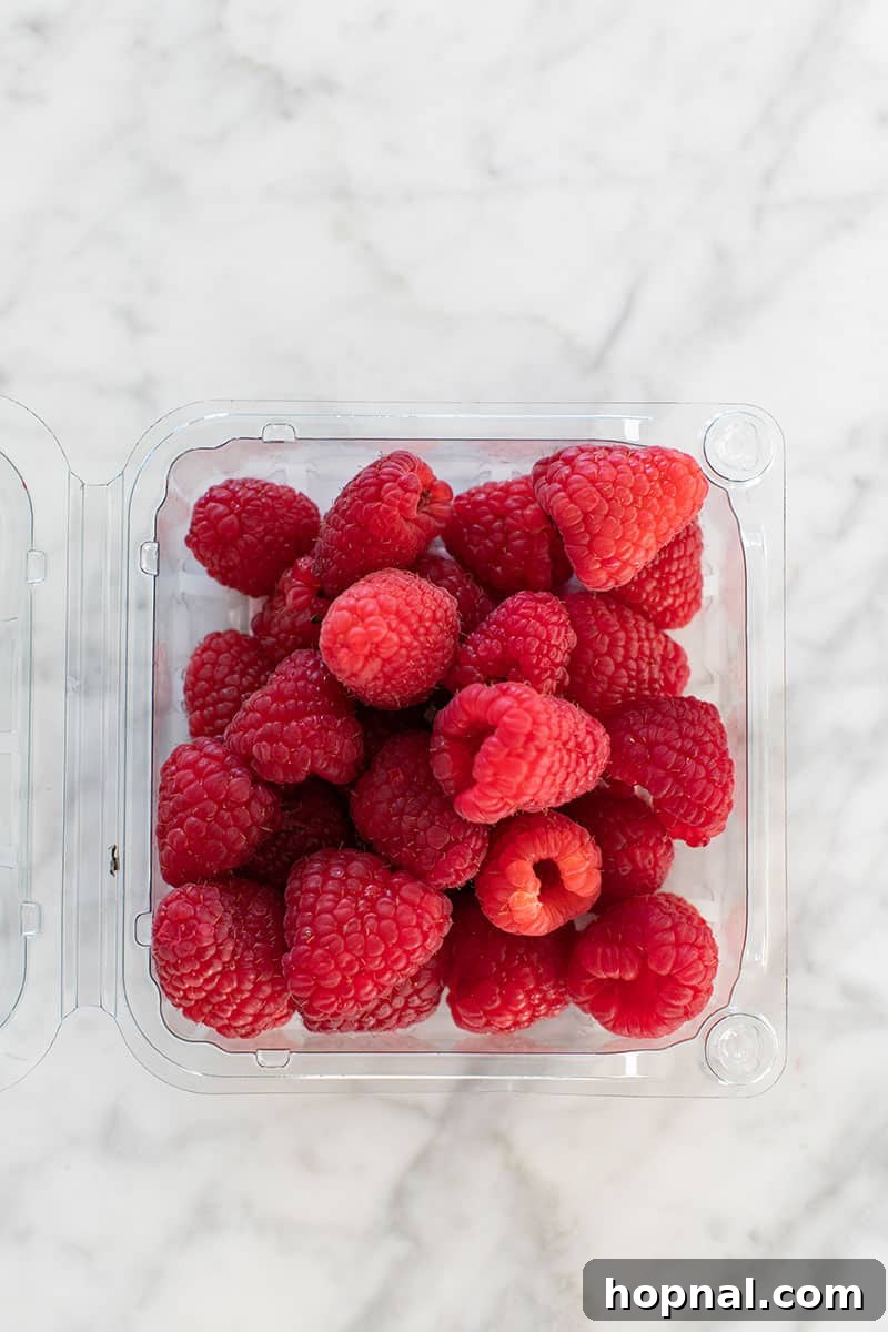 Valentine's Day Sweetheart's Grazing Board 14 A container brimming with fresh, ripe raspberries, their vibrant red color and delicate texture making them an ideal and refreshing component for a dessert platter.