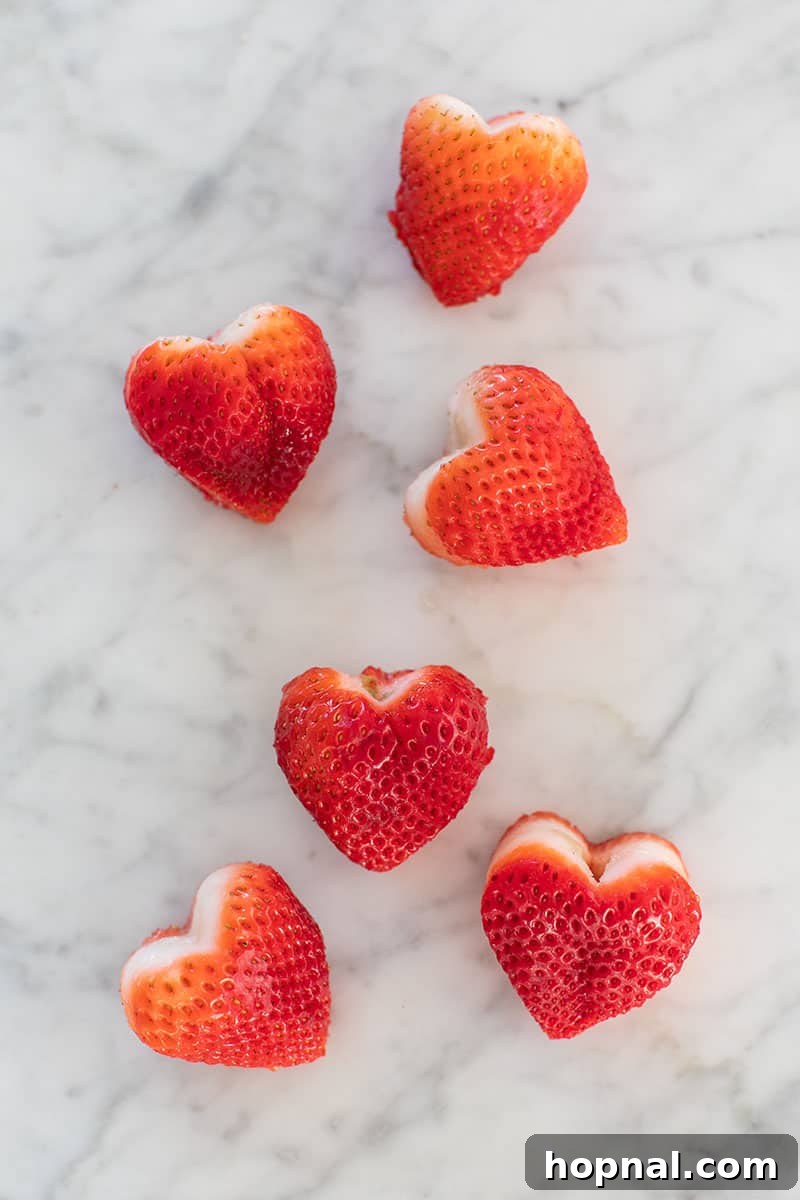 Valentine's Day Sweetheart's Grazing Board 16 Perfectly cut heart-shaped strawberries, ready to adorn a romantic Valentine's Day platter, symbolizing love and fresh delight.