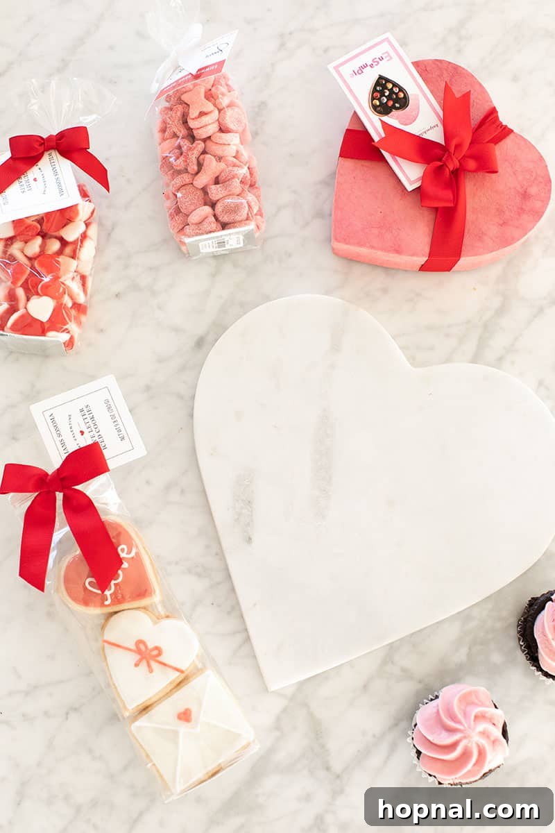 Valentine's Day Sweetheart's Grazing Board 4 A stunning marble heart-shaped platter, beautifully adorned with an array of gourmet cookies and festive cupcakes, meticulously arranged to create a visually appealing and delicious dessert platter.
