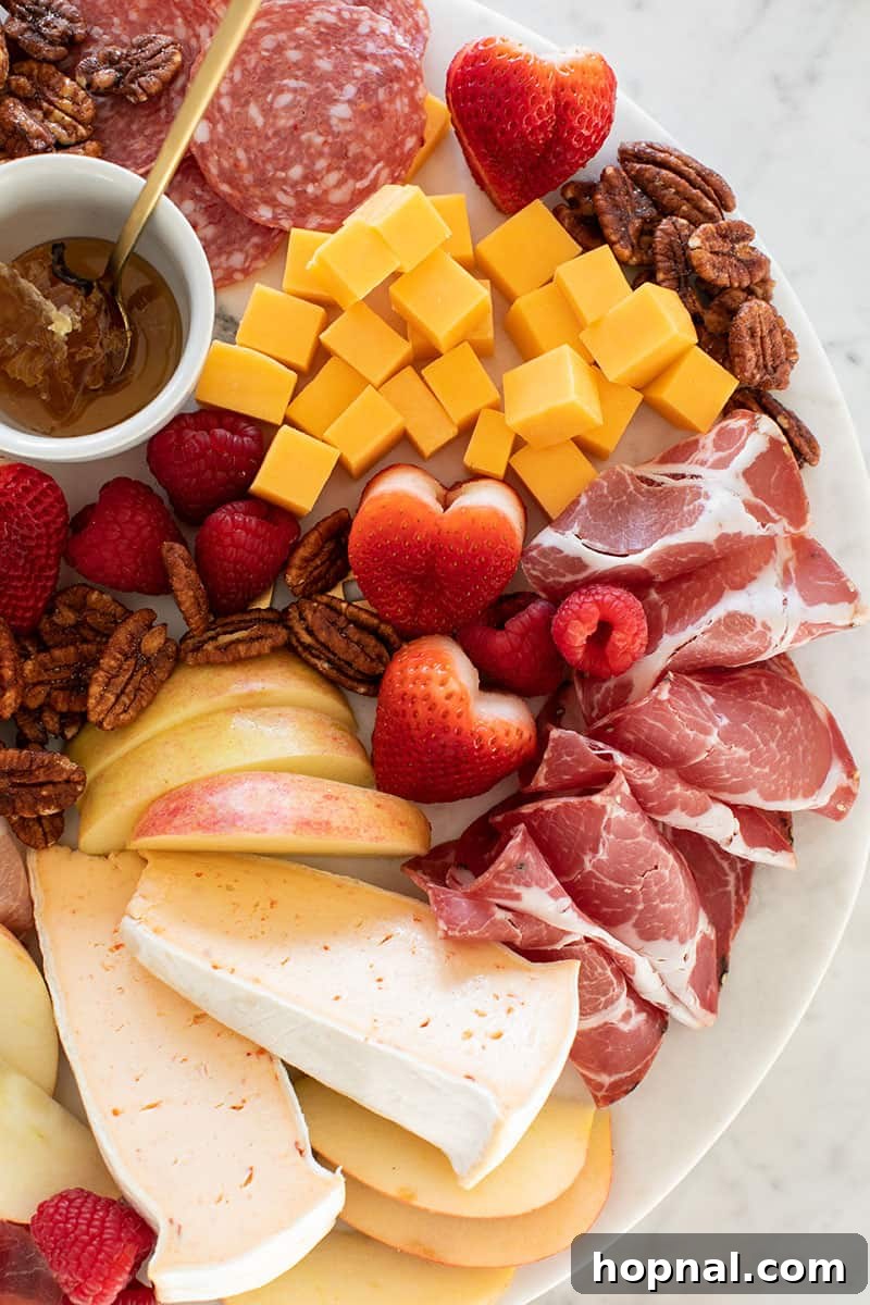 Valentine's Day Sweetheart's Grazing Board 8 A gourmet charcuterie board featuring an exquisite selection of meats and cheeses, beautifully arranged with heart-shaped strawberries, creating a perfect romantic spread.