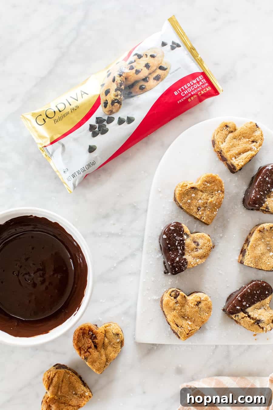 Your Secret to Irresistible Blondies 9 Heart shaped blondies on a marble platter with GODIVA chocolate and a bowl of melted chocolate - white chocolate chips, container at room temperature