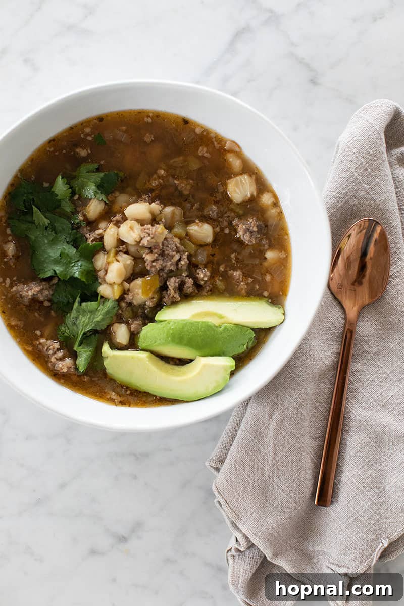 Hominy Soup The Ultimate Winter Comfort 2 Warm bowl of Pozole soup, garnished with fresh cilantro and lime wedges, showcasing its rich broth and tender hominy.