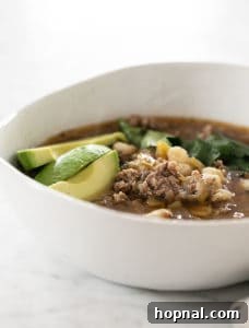 Bowl of pozole soup with avocado and cilantro