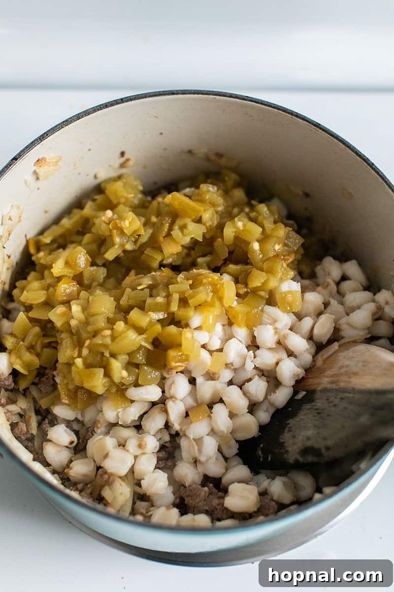 Hominy Soup The Ultimate Winter Comfort 8 A mix of vibrant green chilis, plump hominy, and savory pork simmering together in a Dutch oven, forming the core of the pozole.