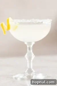 A freshly strained lemon drop martini being poured into a coupe glass, ready for enjoyment.