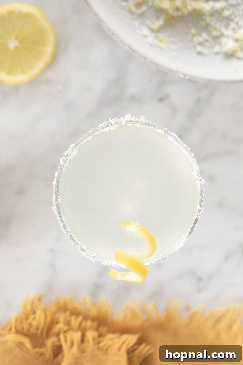 A close-up of a sparkling Lemon Drop Martini, artfully presented in a coupe glass with a sugared rim and a delicate lemon twist garnish.