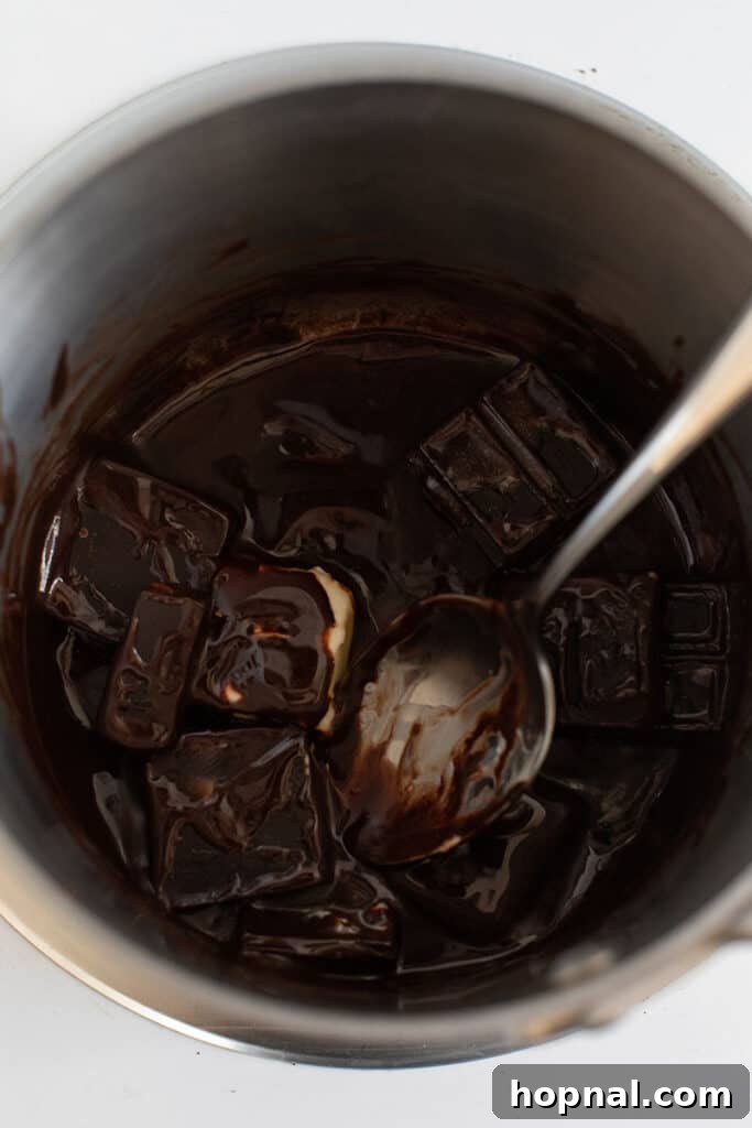 Unsweetened chocolate squares and cubes of butter gently melting together in a saucepan over low heat, forming a rich, glossy base for homemade brownies.