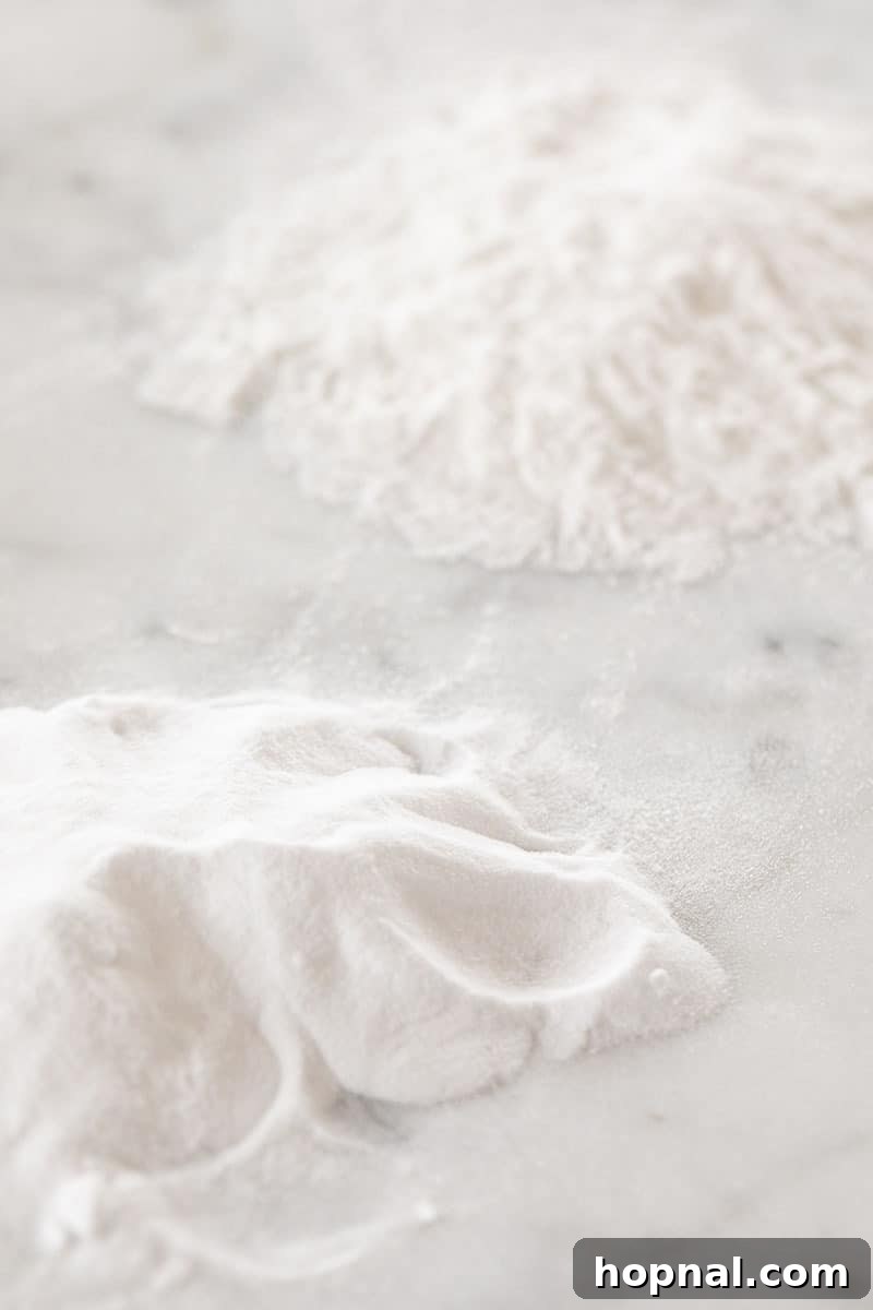 Piles of baking soda and baking powder on a pristine marble surface.