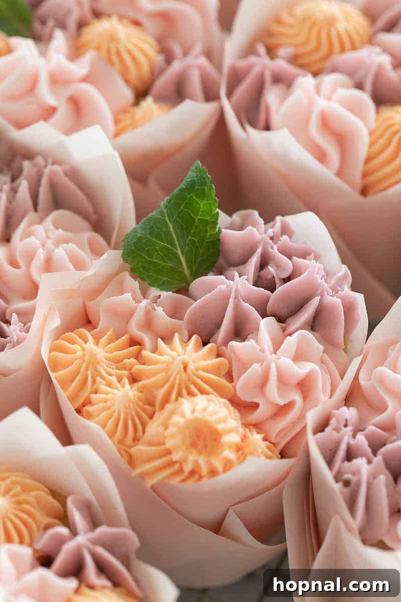A single floral cupcake beautifully decorated with a buttercream flower and a delicate mint leaf, highlighting the exquisite details.