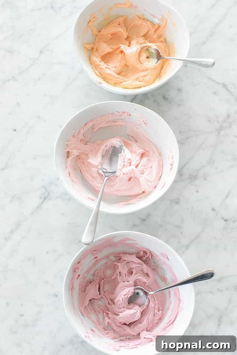 Three bowls of vibrantly colored buttercream frosting, ready for piping onto cupcakes.