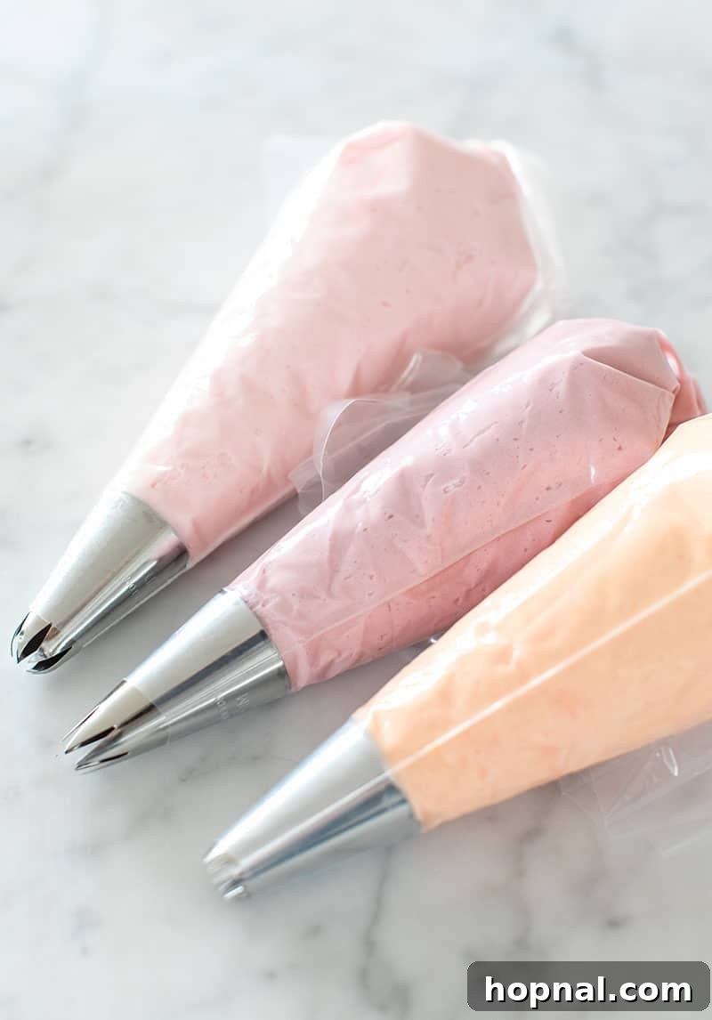 Piping bags filled with colorful buttercream frosting and fitted with various flower-making tips.
