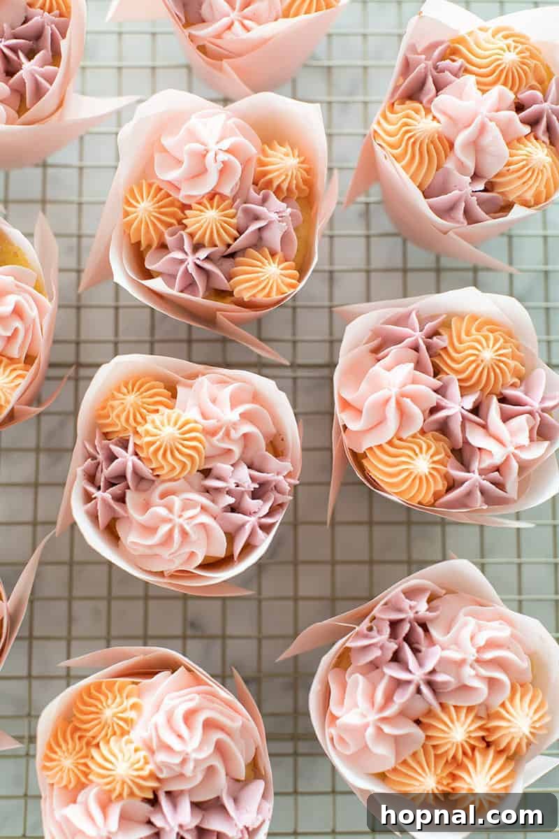 A stunning cupcake flower bouquet featuring various buttercream flower designs in vibrant pink tulip wrappers.