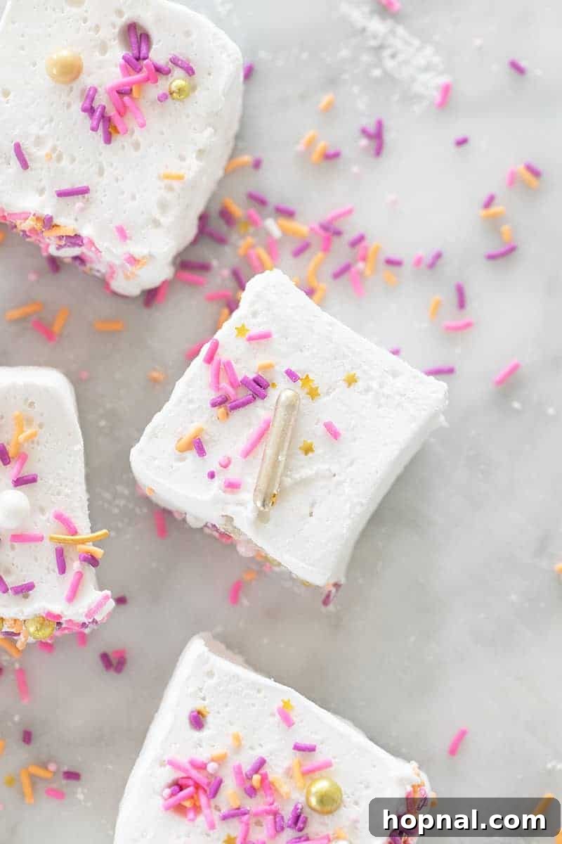 Püfür Püfür Ev Yapımı Marshmallow Sırları 11 Delightfully soft, square-cut homemade marshmallows generously dusted with powdered sugar and adorned with a cheerful array of rainbow sprinkles, showcased up close and invitingly.