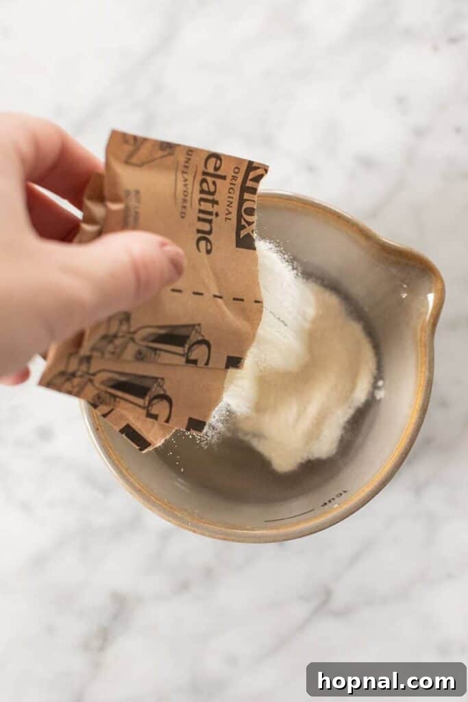 Püfür Püfür Ev Yapımı Marshmallow Sırları 6 Unflavored gelatin granules are gently poured into a small bowl, ready to be bloomed with water, forming a soft, cohesive mass that will provide structure.