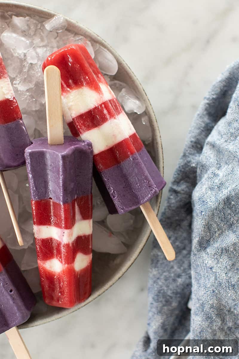 Several homemade Bomb Pop popsicles, perfectly striped and chilling over a bed of ice, ready to be served.