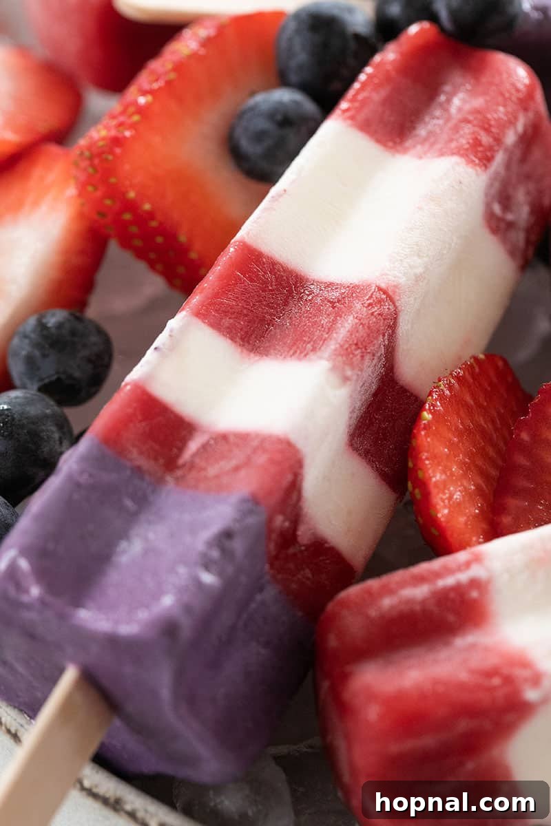 Close-up shot of a single homemade Bomb Pop popsicle, showing its distinct red, white, and blue layers and creamy texture.