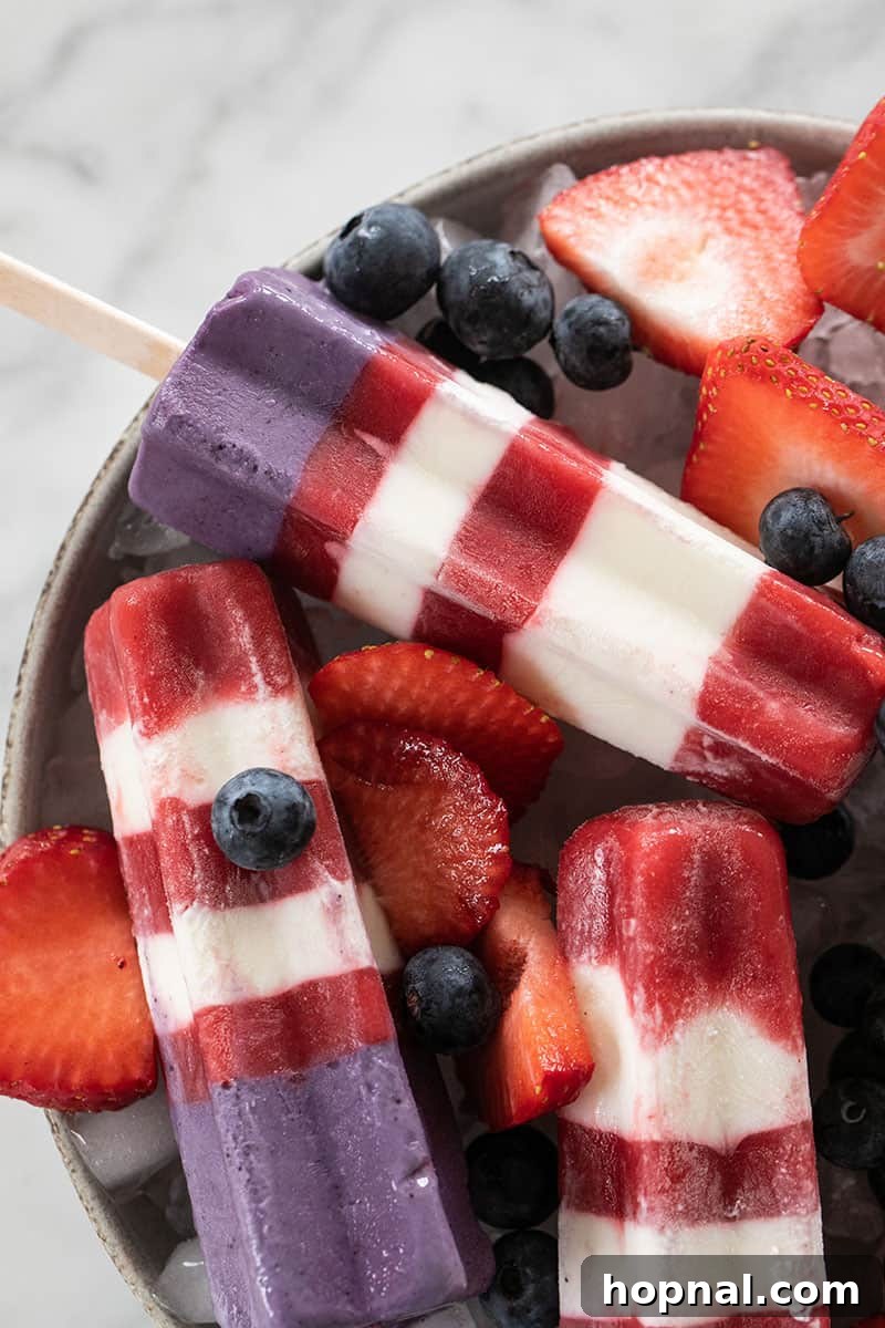 Collection of homemade Bomb Pop popsicles, perfectly striped in red, white, and blue, showcasing the vibrant layers.