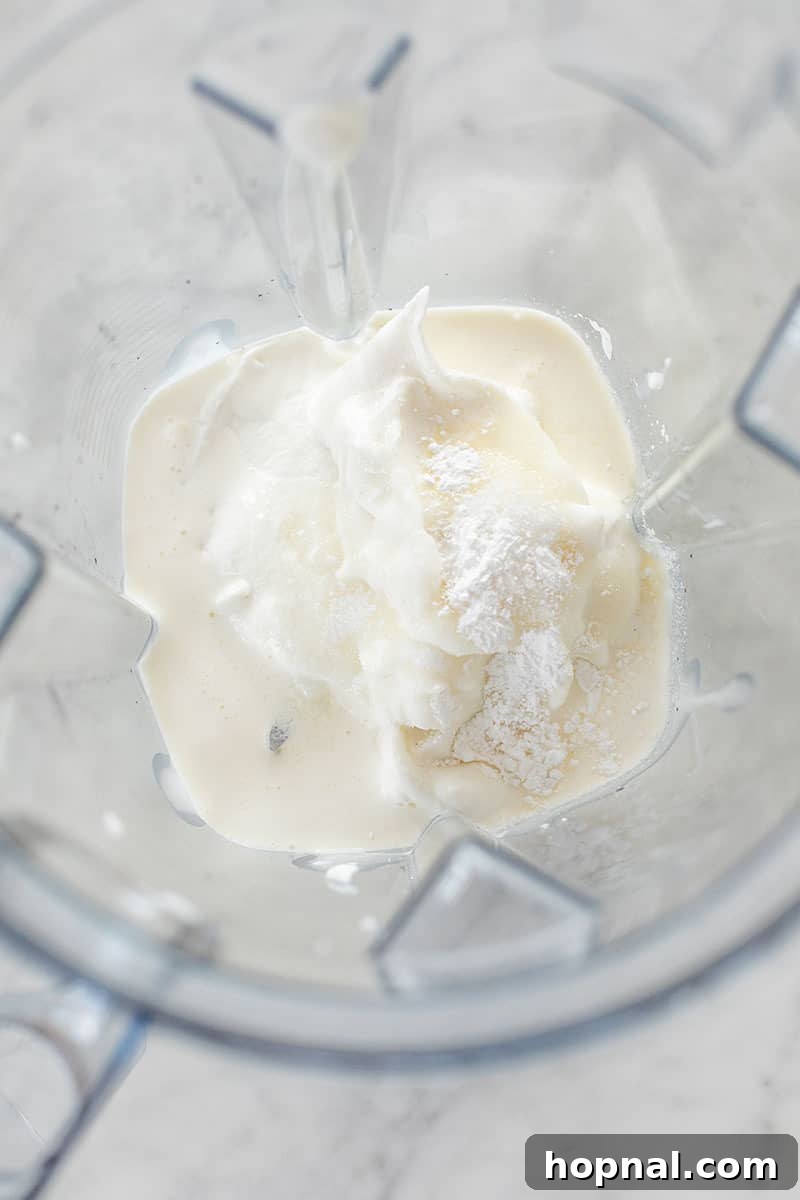 Creamy milk and vanilla yogurt being blended together in a high-speed blender, creating the white layer for popsicles.