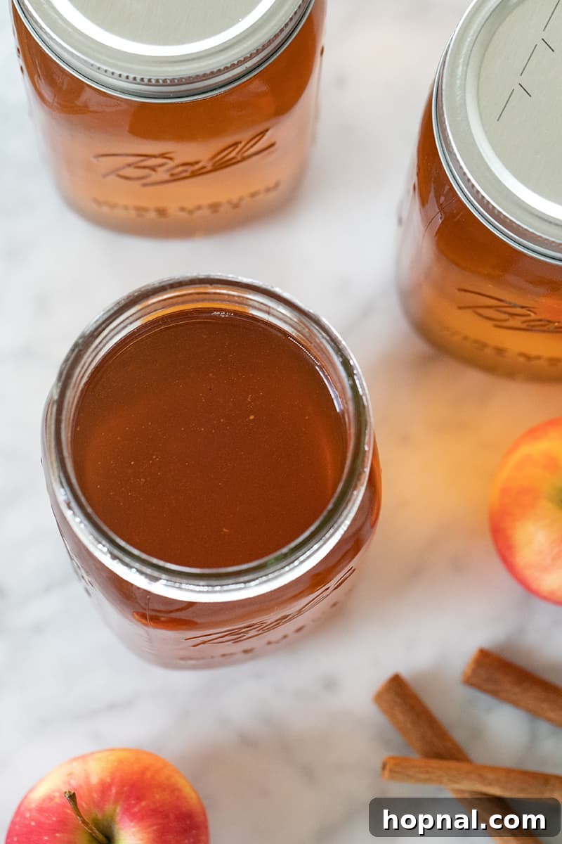 Neatly arranged glass jars filled with homemade apple pie moonshine, ready for storage or gifting.