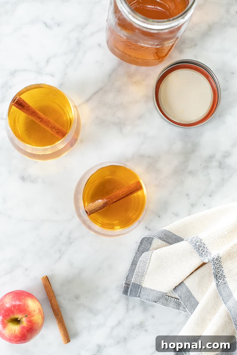 Glasses of apple pie moonshine artfully arranged on a sleek marble table, suggesting a sophisticated serving.