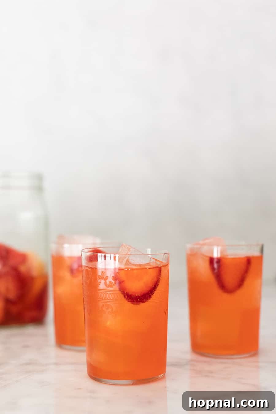 Glasses of perfectly chilled strawberry lemonade, ready to be enjoyed, with a blurred background of fresh strawberries.