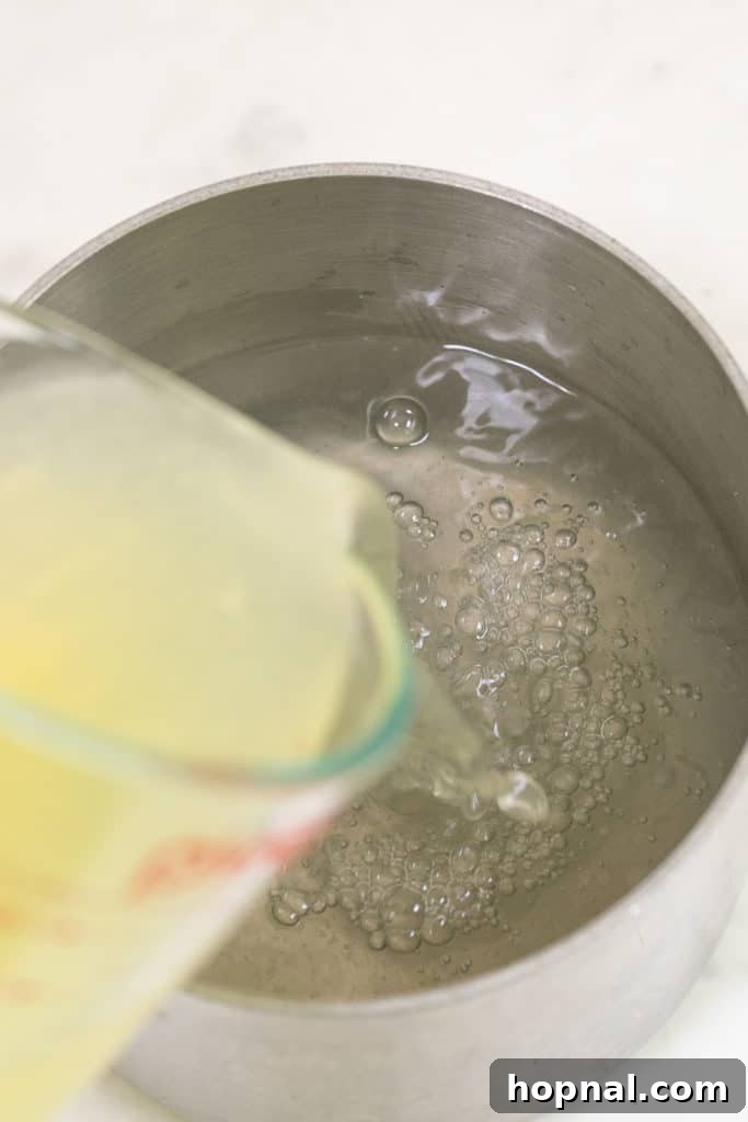 Lemon juice being freshly squeezed or poured into a measuring cup or pot, highlighting the raw ingredients.