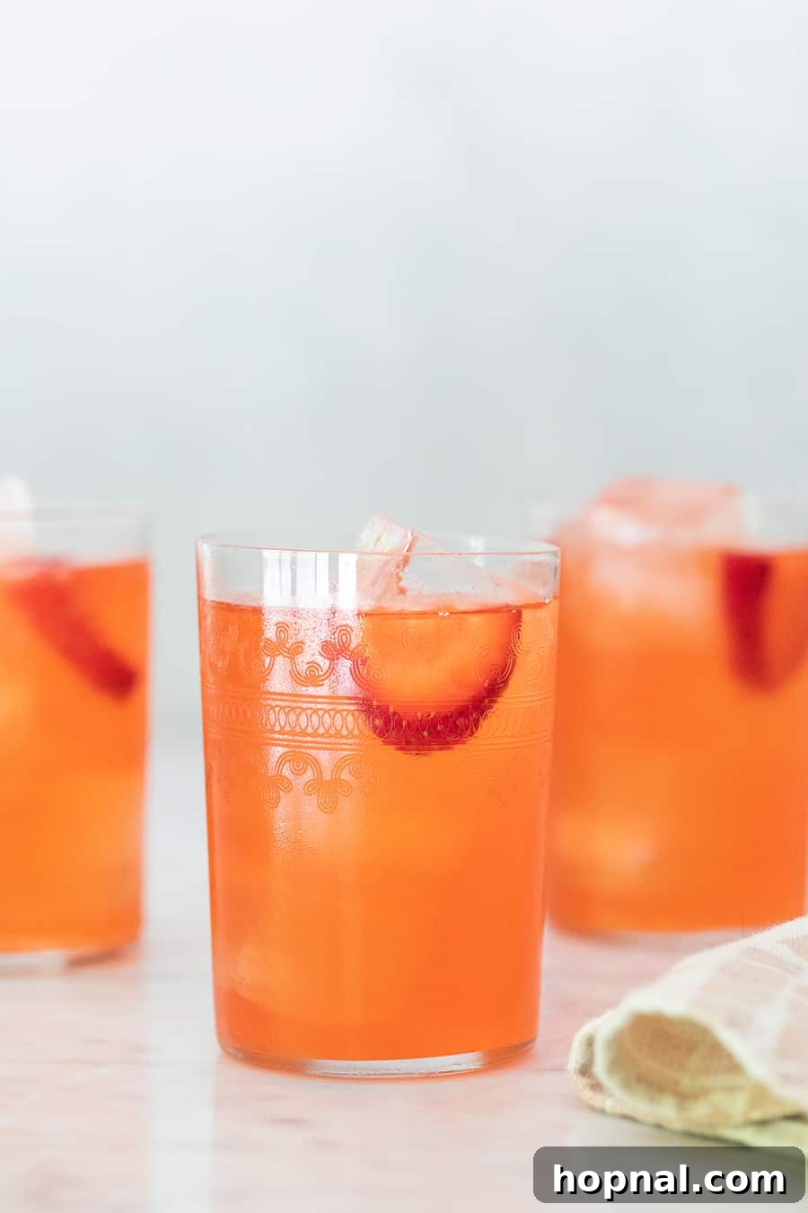 Multiple servings of strawberry lemonade in elegant glasses, perhaps at a party or social gathering.