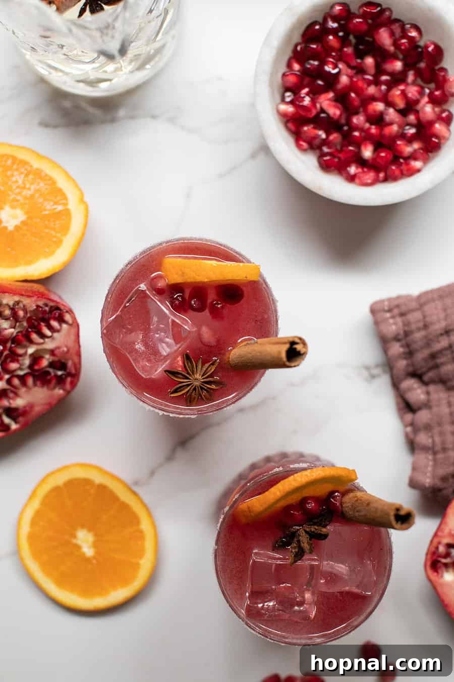 Crimson Spice Margarita 2 Pomegranate Margarita with orange slice and fresh pomegranates.