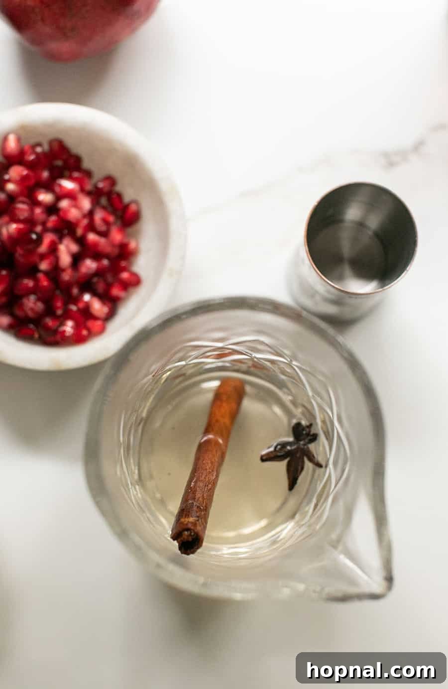 Crimson Spice Margarita 6 Cinnamon simple syrup with a cocktail jigger and fresh pomegranates.