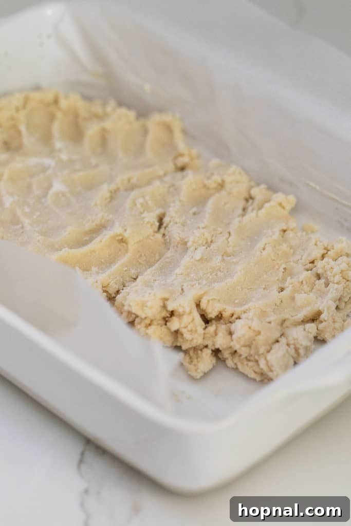 Buttery Shortbread Bars 5 Shortbread dough being pressed evenly into a prepared baking dish.