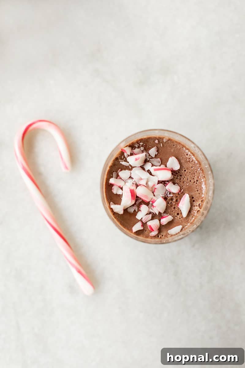 Two chocolate Panna cotta desserts in clear glasses with crushed candy canes, showcasing a festive presentation.