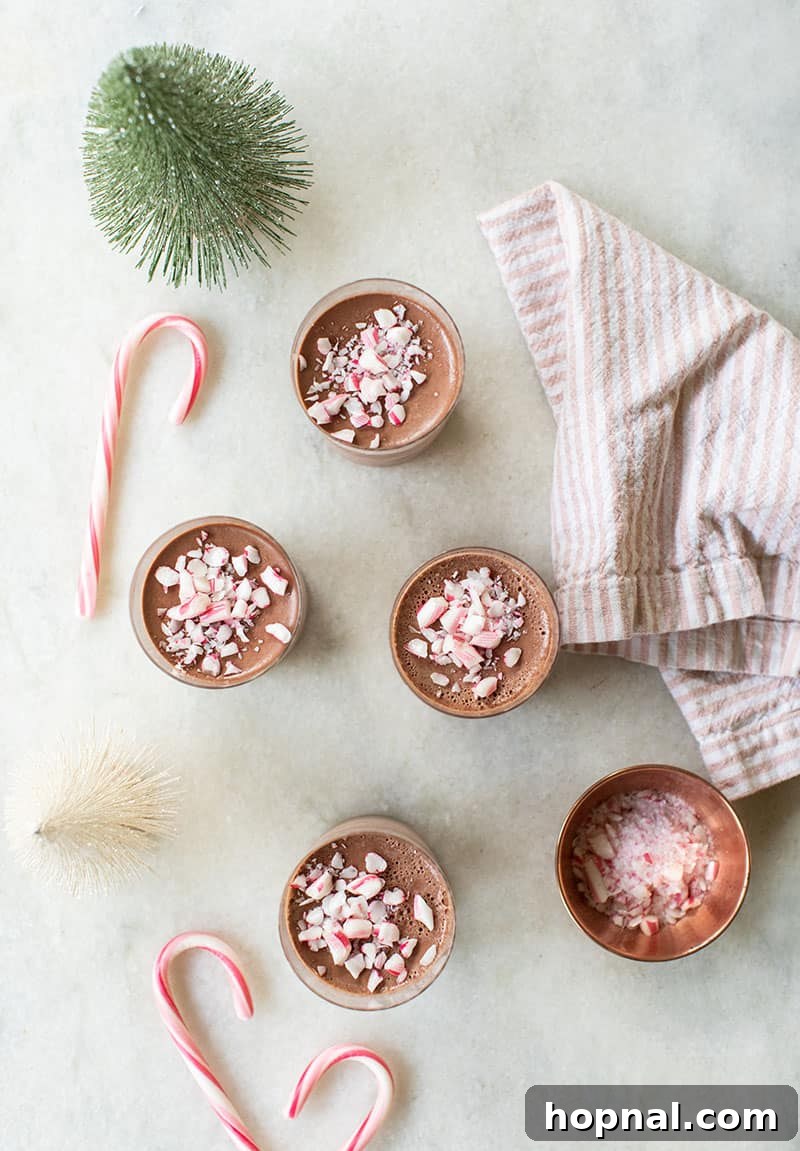 Three individual servings of peppermint chocolate Panna cotta in small glasses, topped with generous amounts of crushed candy canes, ready for serving.