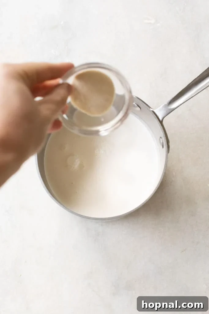 Sprinkling gelatin over cold water in a small bowl to bloom, a crucial first step for smooth panna cotta.
