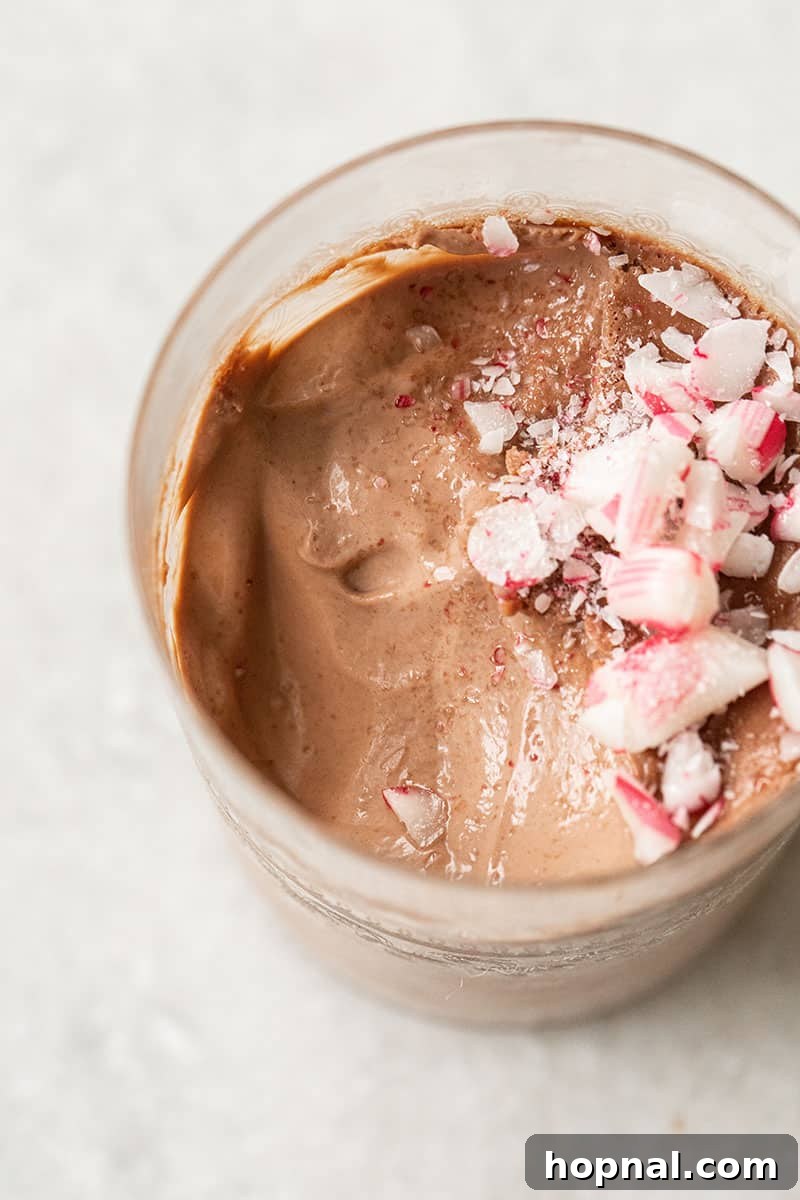 A close-up shot of a rich chocolate panna cotta in a glass, generously topped with crushed candy canes for a festive and minty flavor.