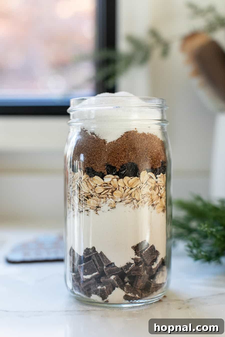 Close-up view of a glass jar filled with perfectly layered dry cookie mix ingredients, showcasing distinct colors and textures.