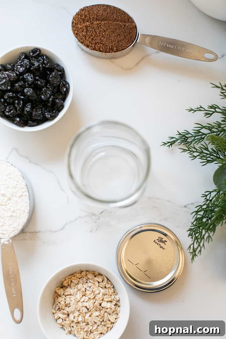 An organized collection of dry ingredients and tools laid out on a table, ready for assembling cookie mixes in a jar.