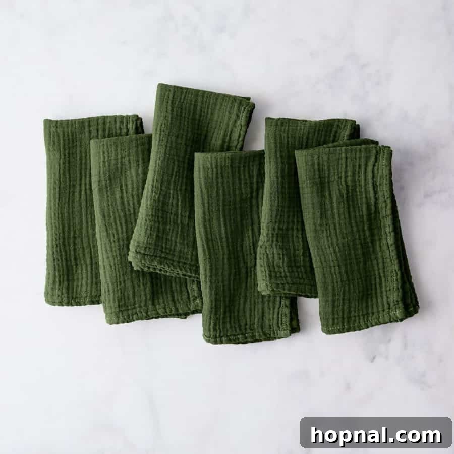 Sparkling Christmas Tablescapes 12 Beautiful green napkins folded elegantly on a Christmas table setting.