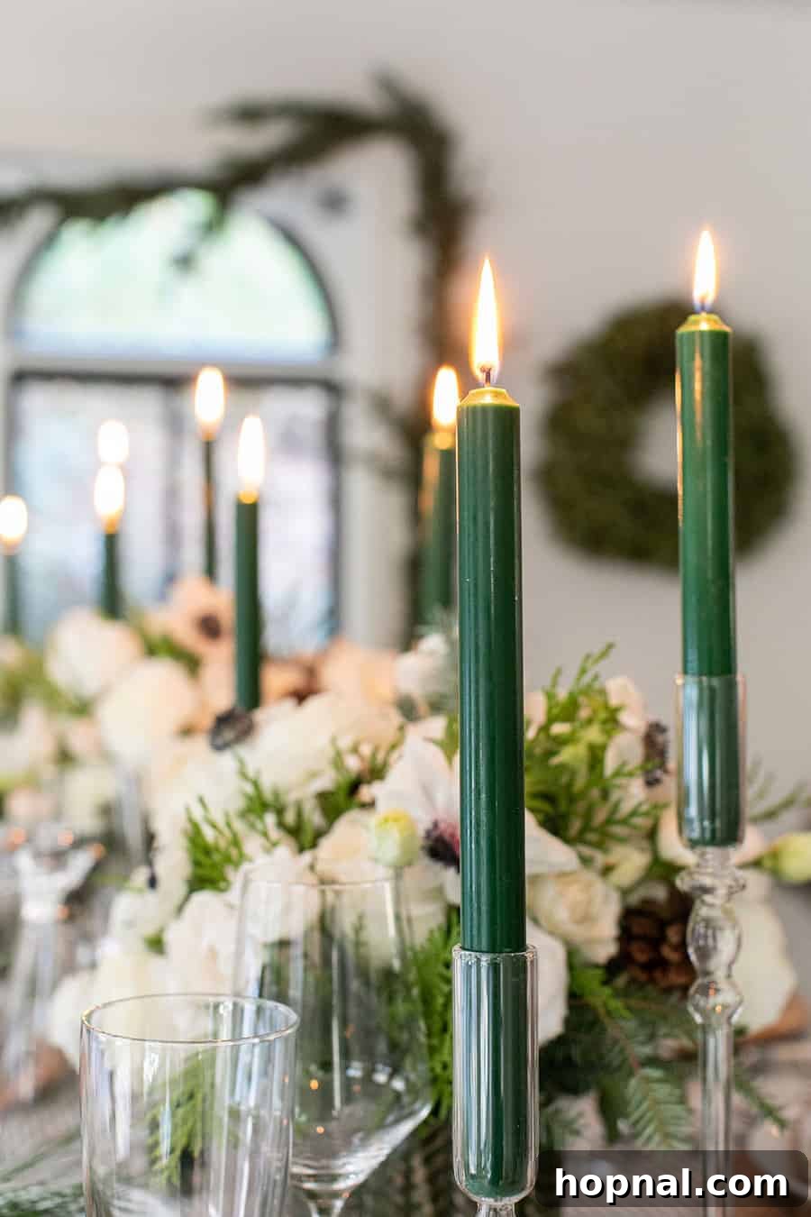 Sparkling Christmas Tablescapes 22 Close-up of elegant green tapered candles in sleek candle holders, casting a warm glow on Christmas table decorations.