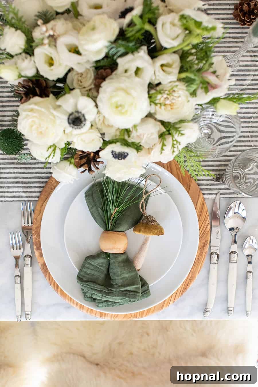 Sparkling Christmas Tablescapes 6 A close-up of a festive Christmas table setting, showcasing a green napkin, an elegant olive wood charger, and classic white plates from Williams Sonoma.