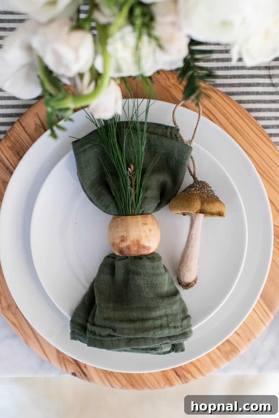 Sparkling Christmas Tablescapes 8 A close-up of a festive Christmas table setting with a green napkin, a rustic wooden napkin ring, and a charming mushroom ornament.
