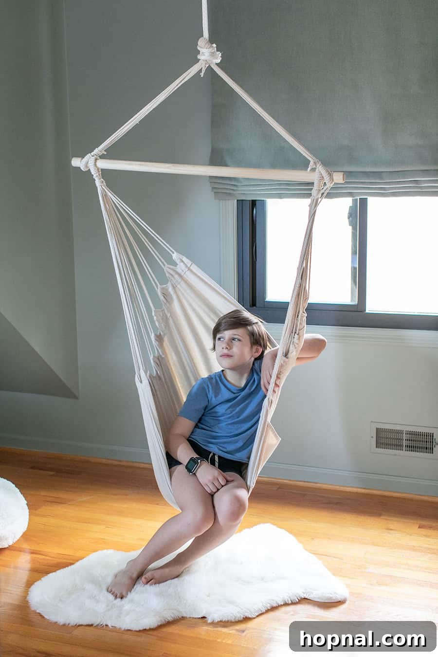 A child enjoys the hanging chair in a woodsy-themed kids bedroom, highlighting fun and unique furniture ideas for cabin rooms.