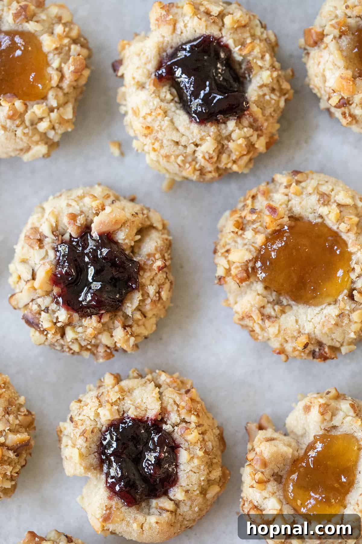 Exquisite Jam Thumbprint cookies, golden brown and rolled in crushed walnuts, with vibrant red jam centers. Perfect for holidays or any sweet craving.