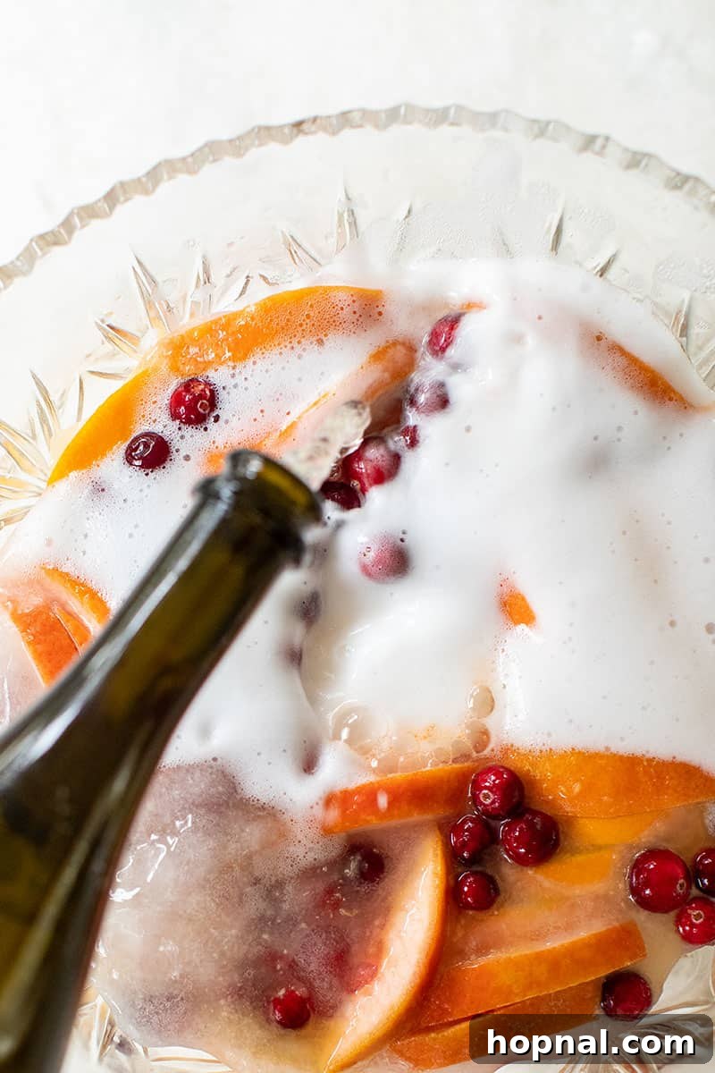 Sparkling Christmas party punch with Champagne, oranges, and cranberries.