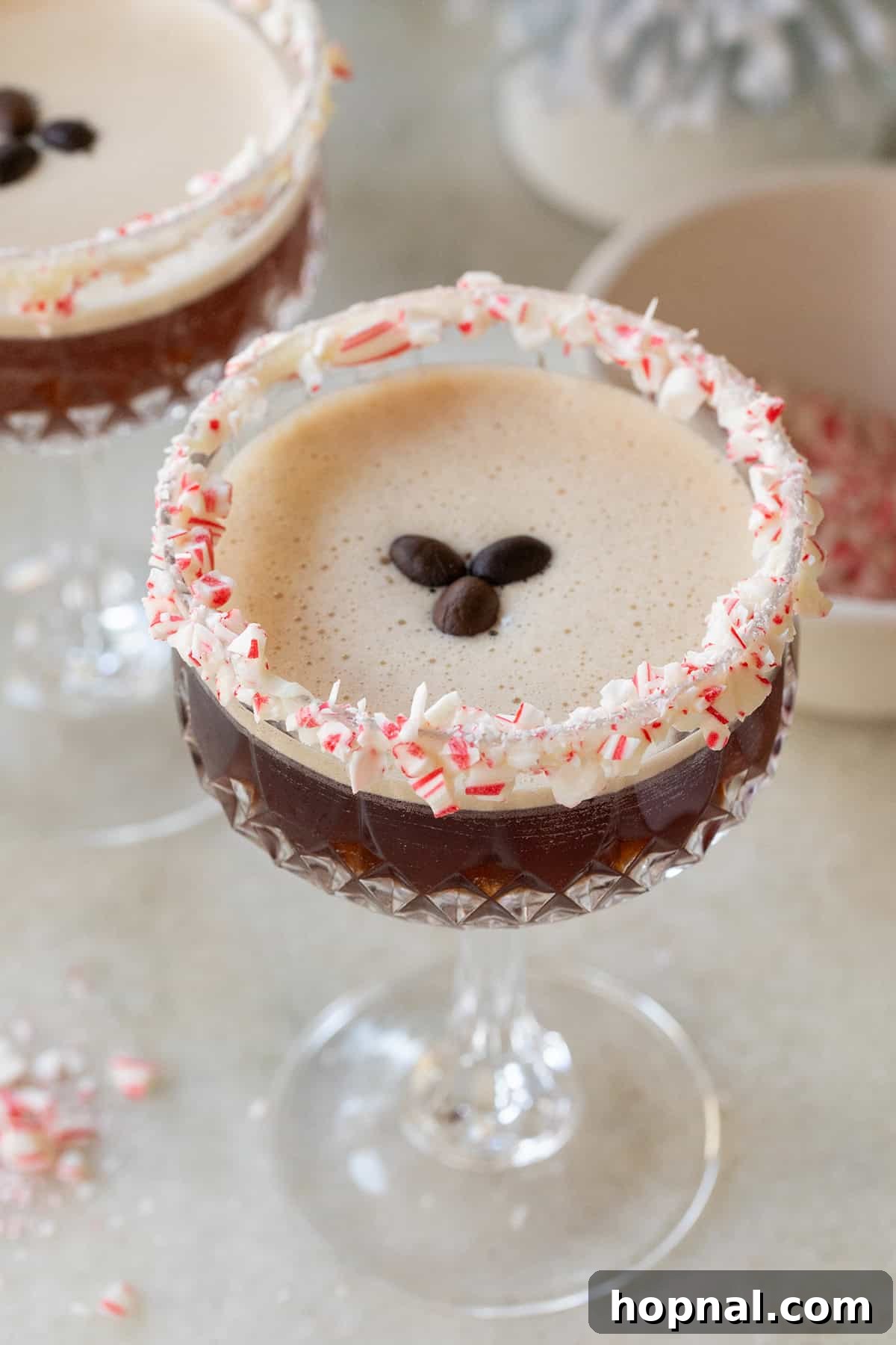Peppermint Espresso Martini with a candy cane rim and coffee beans.