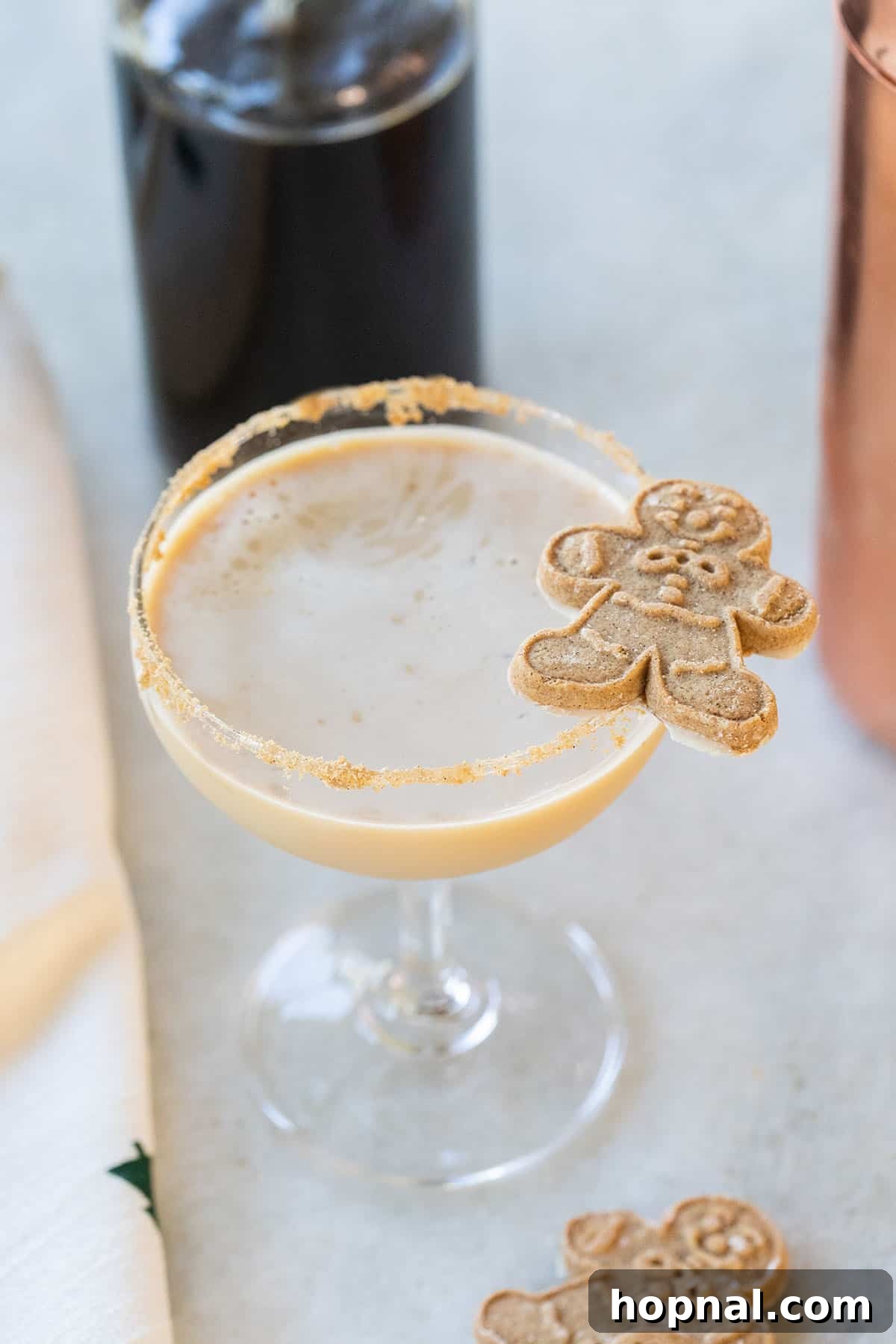 Spiced gingerbread martini recipe garnished with a gingerbread man cookie.